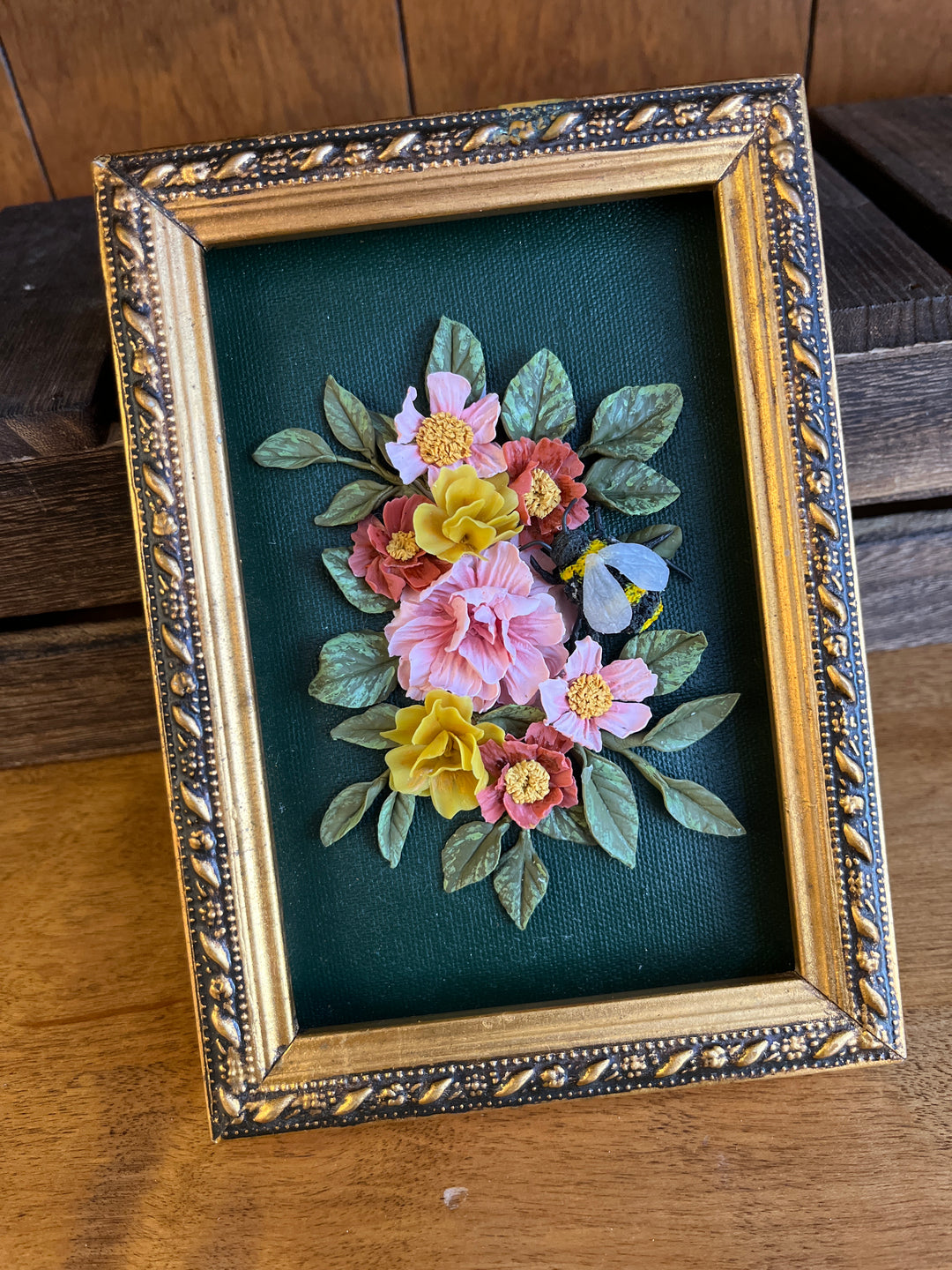 ornate gold frame with clay flowers and bee